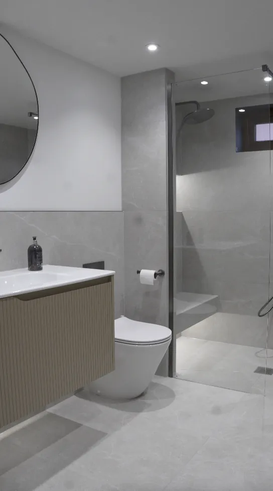 Light grey walk-in shower with frameless glass and built-in bench