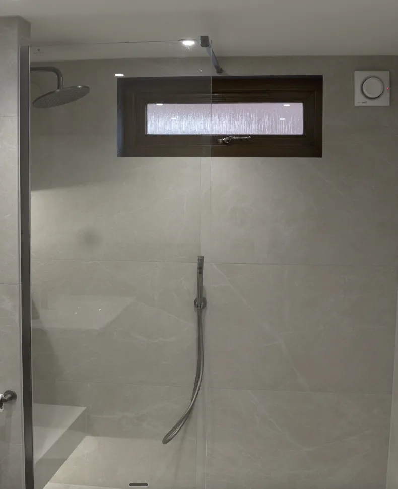 Walk-in shower with large-format grey tiles and gunmetal fittings