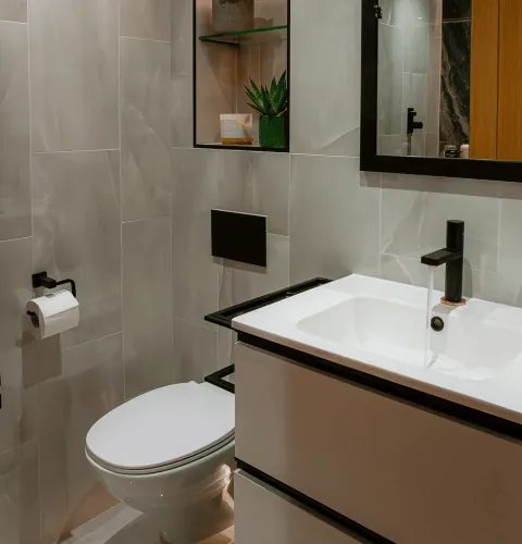 Floating vanity with matte black tap and fittings, grey tiles and a lit shelf niche