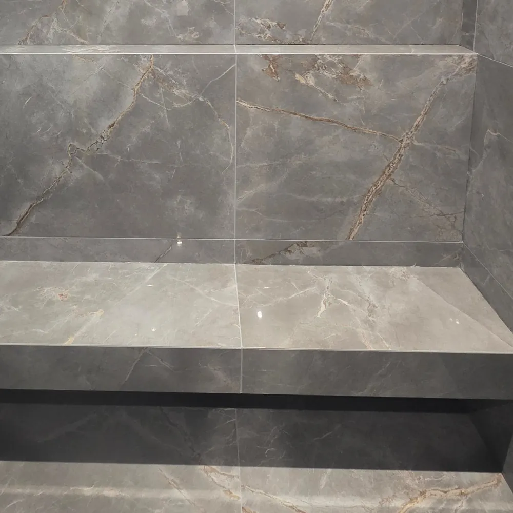 Built-in shower bench and recessed shelf in grey marble-effect tiles