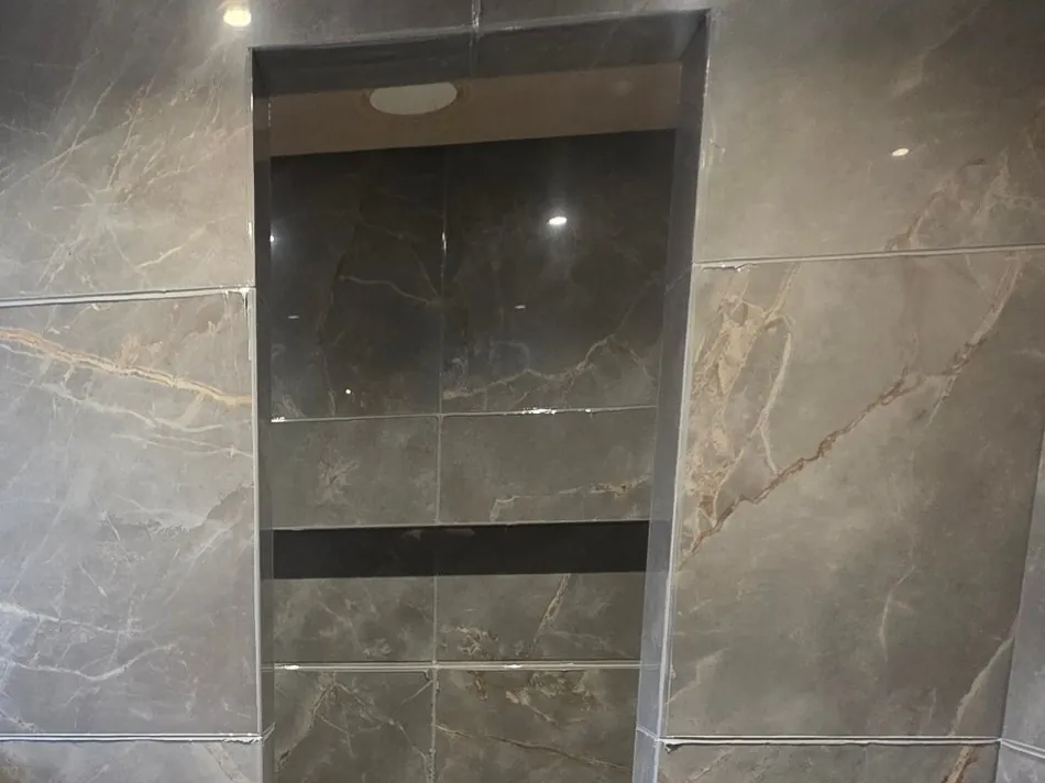 Large-format marble-effect tiling and a recessed shower alcove during fitting